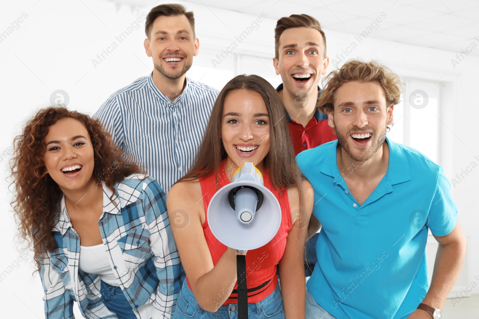 Photo of Group of happy young people with megaphone indoors