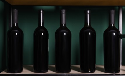 Photo of Bottles of wine on shelf near green wall