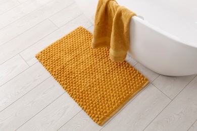 Photo of Soft orange bath mat on floor in bathroom