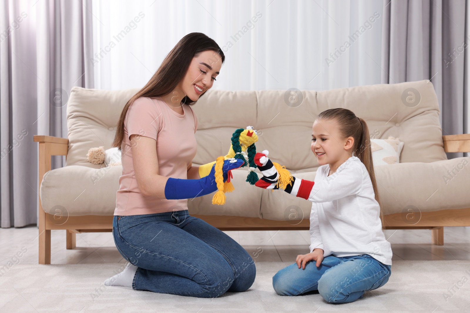 Photo of Happy mother and daughter playing with funny sock puppets together at home