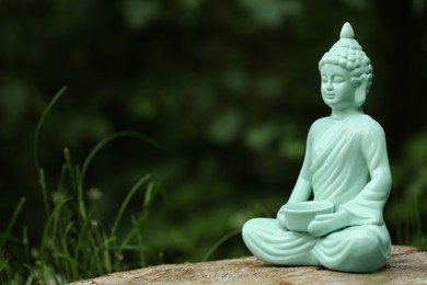 Photo of Decorative Buddha statue on stump outdoors, space for text