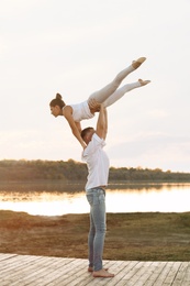 Photo of Beautiful young couple practicing dance moves near river at sunset