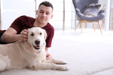 Handsome man with dog lying on carpet at home