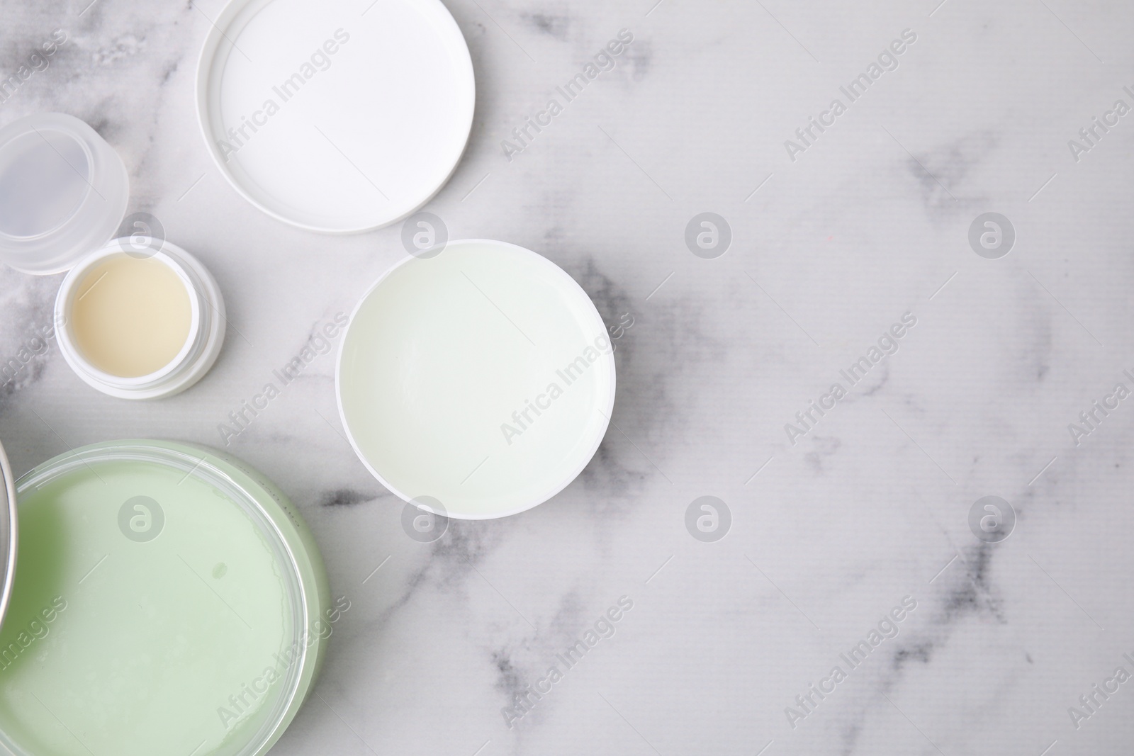 Photo of Jars of petroleum jelly on light gray marble table, flat lay. Space for text