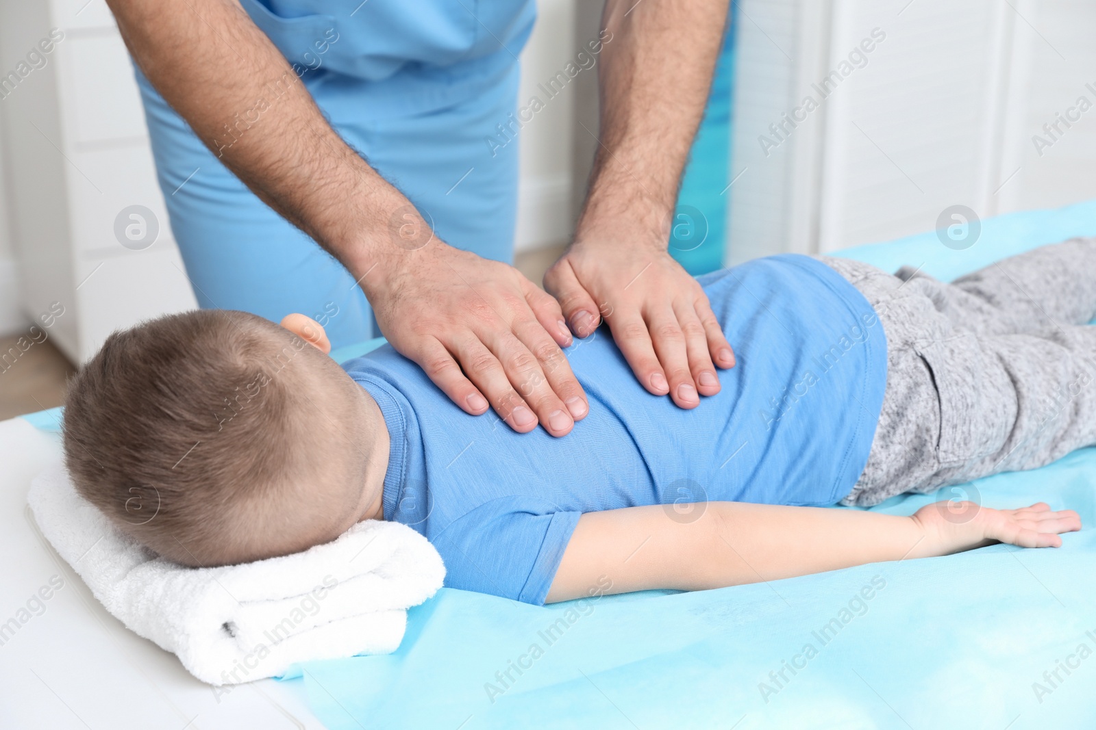 Photo of Orthopedist massaging child's back in clinic, closeup. Scoliosis treatment