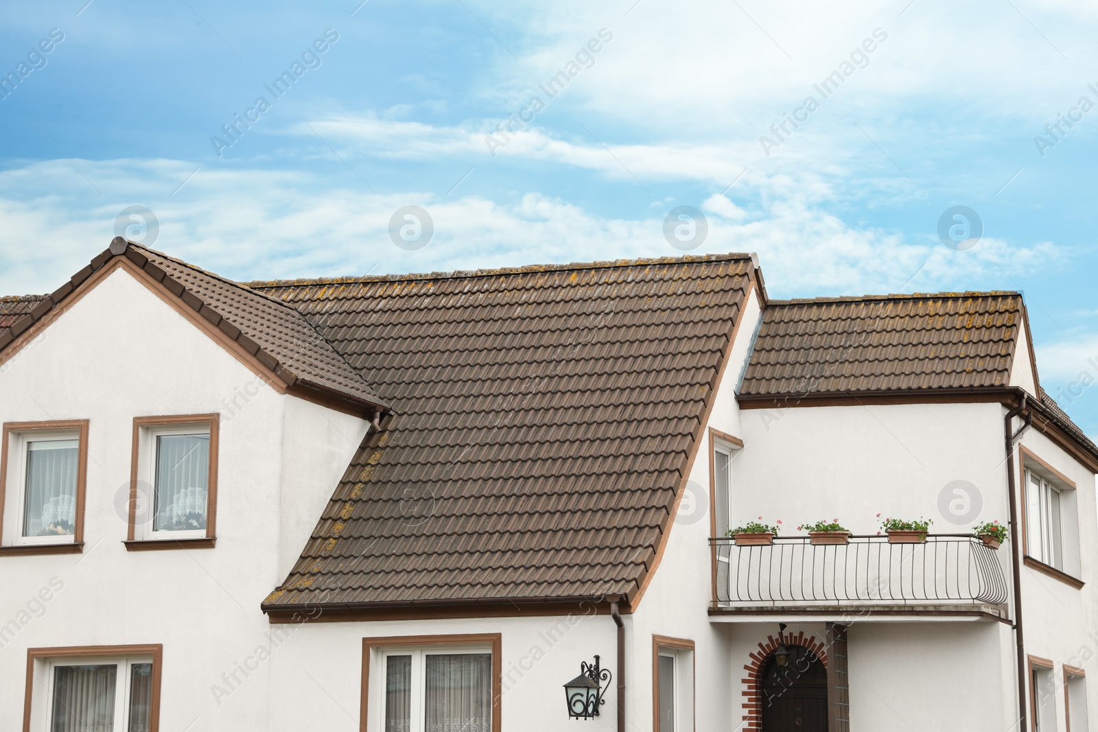 Photo of Beautiful house with brown roof against blue sky