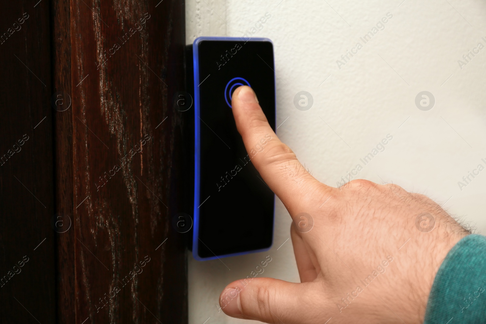 Photo of Man scanning fingerprint on alarm system indoors, closeup