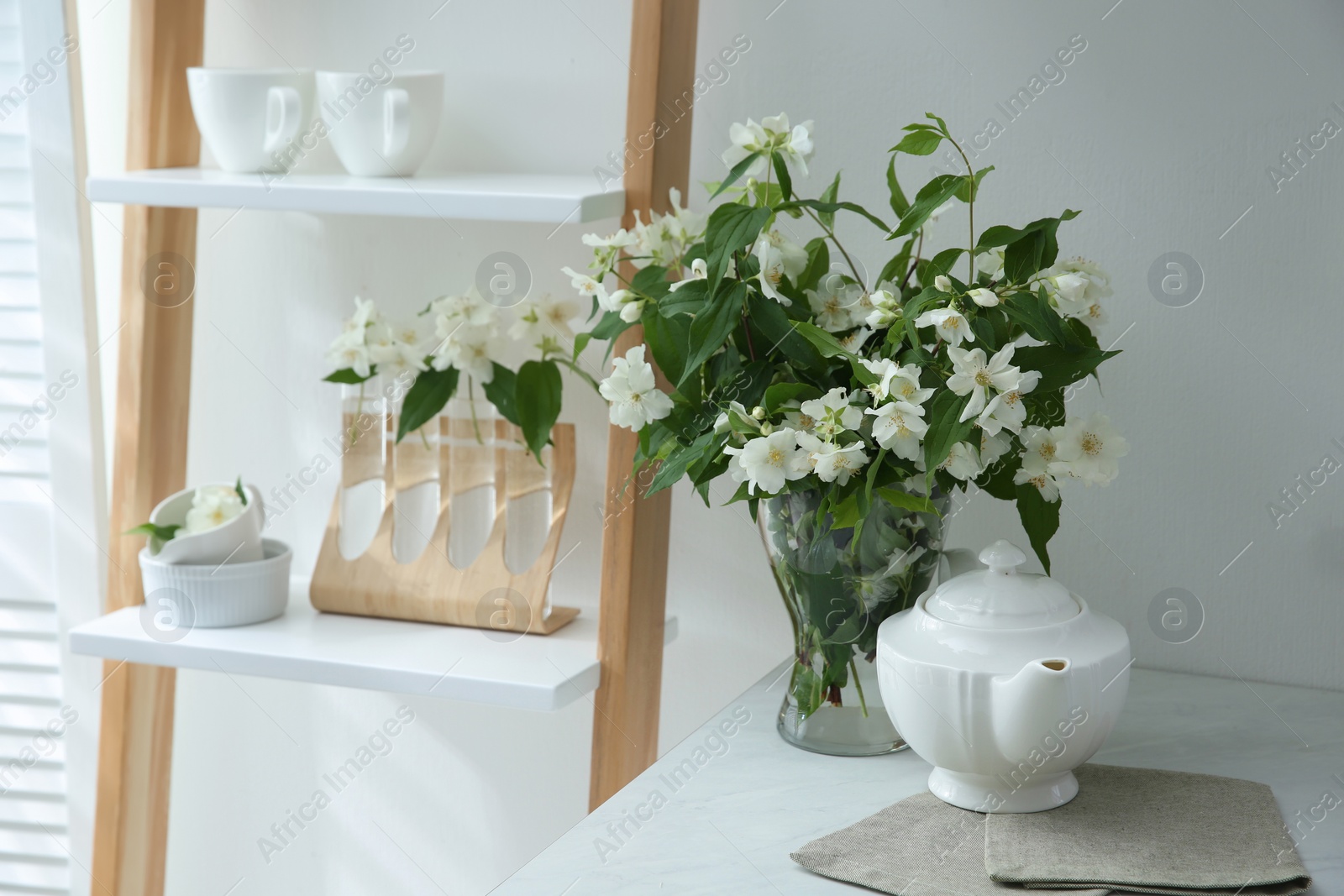 Photo of Bouquet with beautiful jasmine flowers on countertop in kitchen, space for text