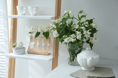 Photo of Bouquet with beautiful jasmine flowers on countertop in kitchen, space for text