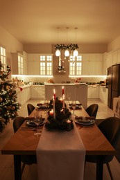 Photo of Festive table setting and beautiful Christmas decor in kitchen. Interior design