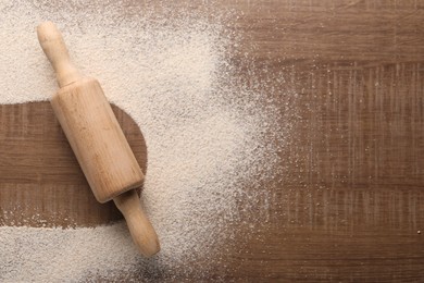 Photo of Imprint of board on wooden table with flour and rolling pin, top view. Space for text