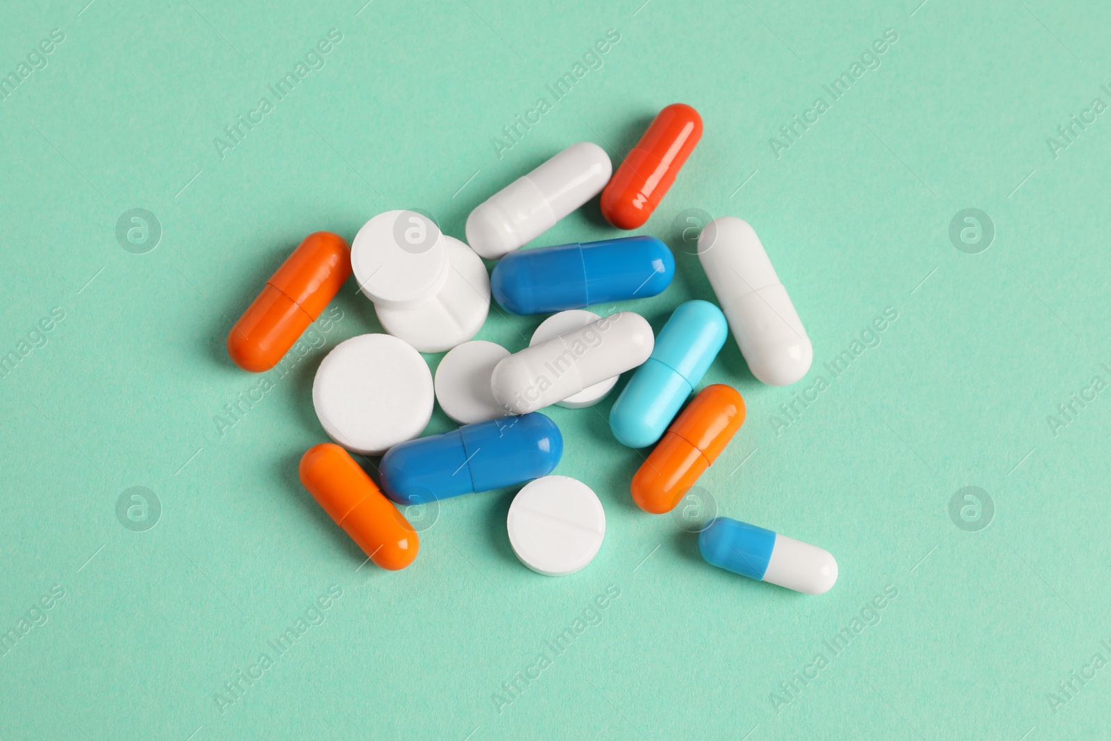 Photo of Pile of colorful pills on green background, flat lay