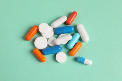 Pile of colorful pills on green background, flat lay