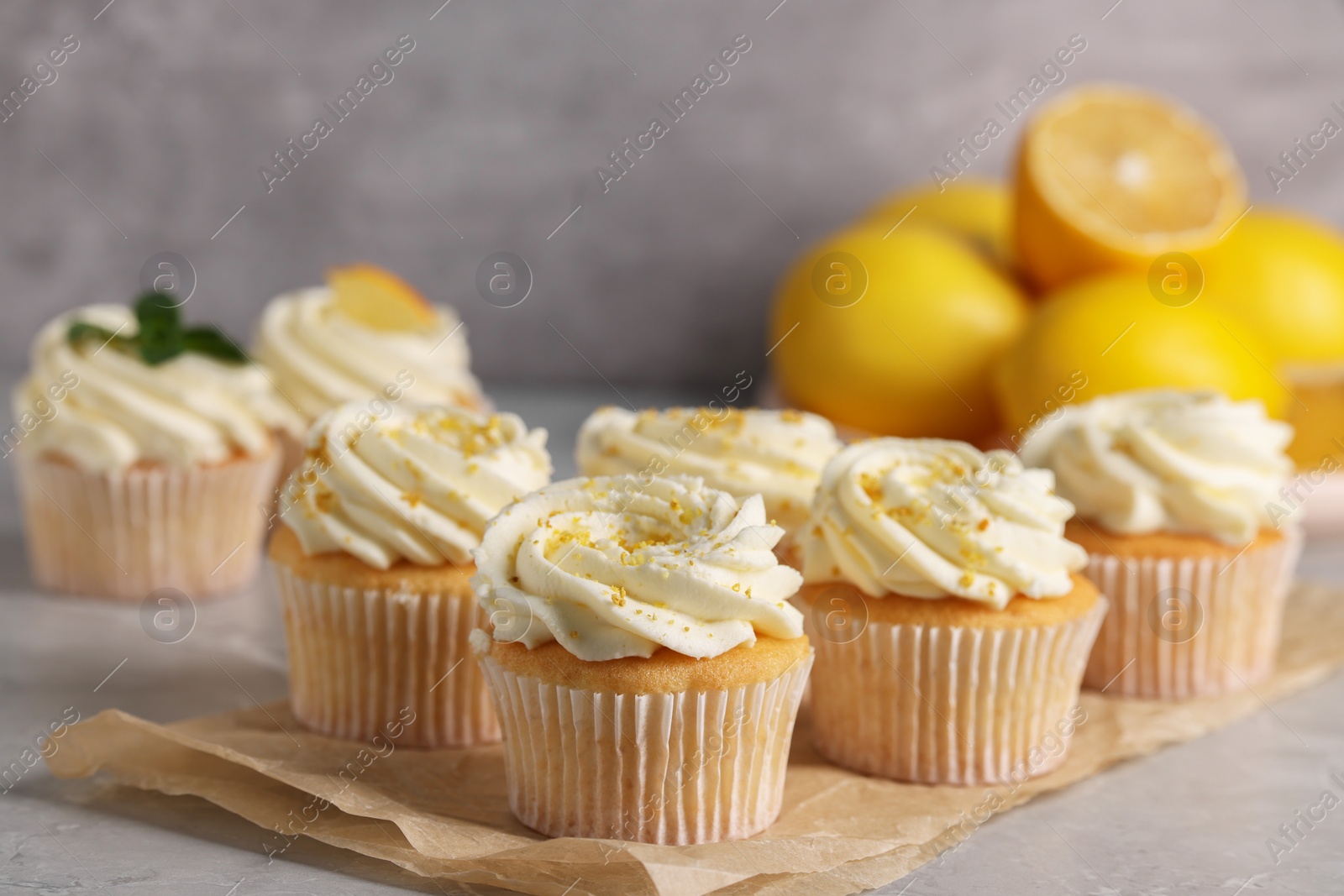 Photo of Delicious cupcakes with white cream and lemon zest on table, closeup