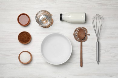 Flat lay composition with instant coffee granules and whisk on white wooden table