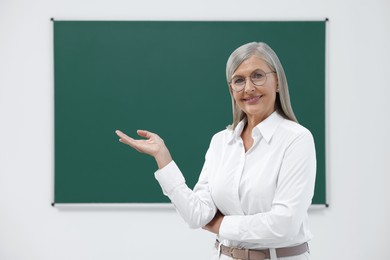 Photo of Portrait of happy professor near blackboard in classroom