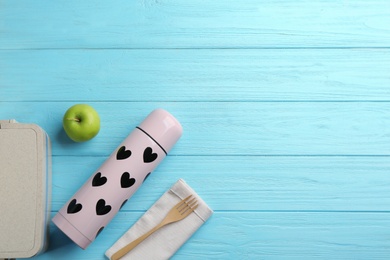 Photo of Flat lay composition with thermos and lunch box on turquoise wooden background, space for text