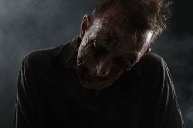 Photo of Scary zombie on dark background, closeup. Halloween monster