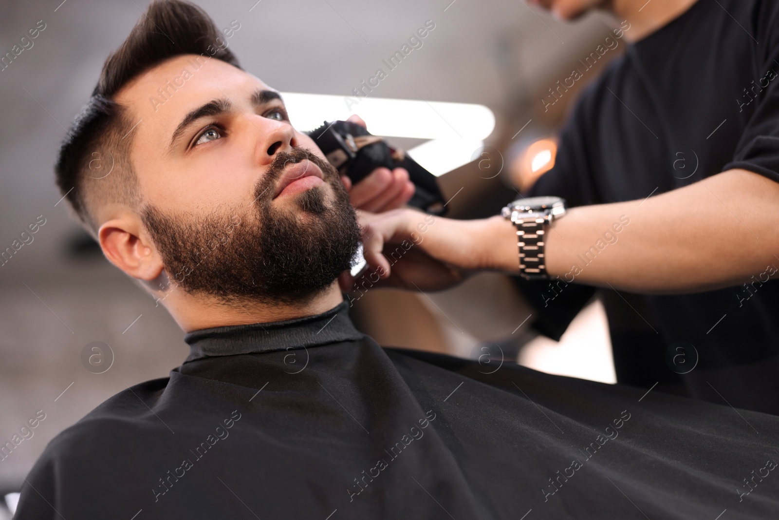 Photo of Professional hairdresser working with client in barbershop, low angle view