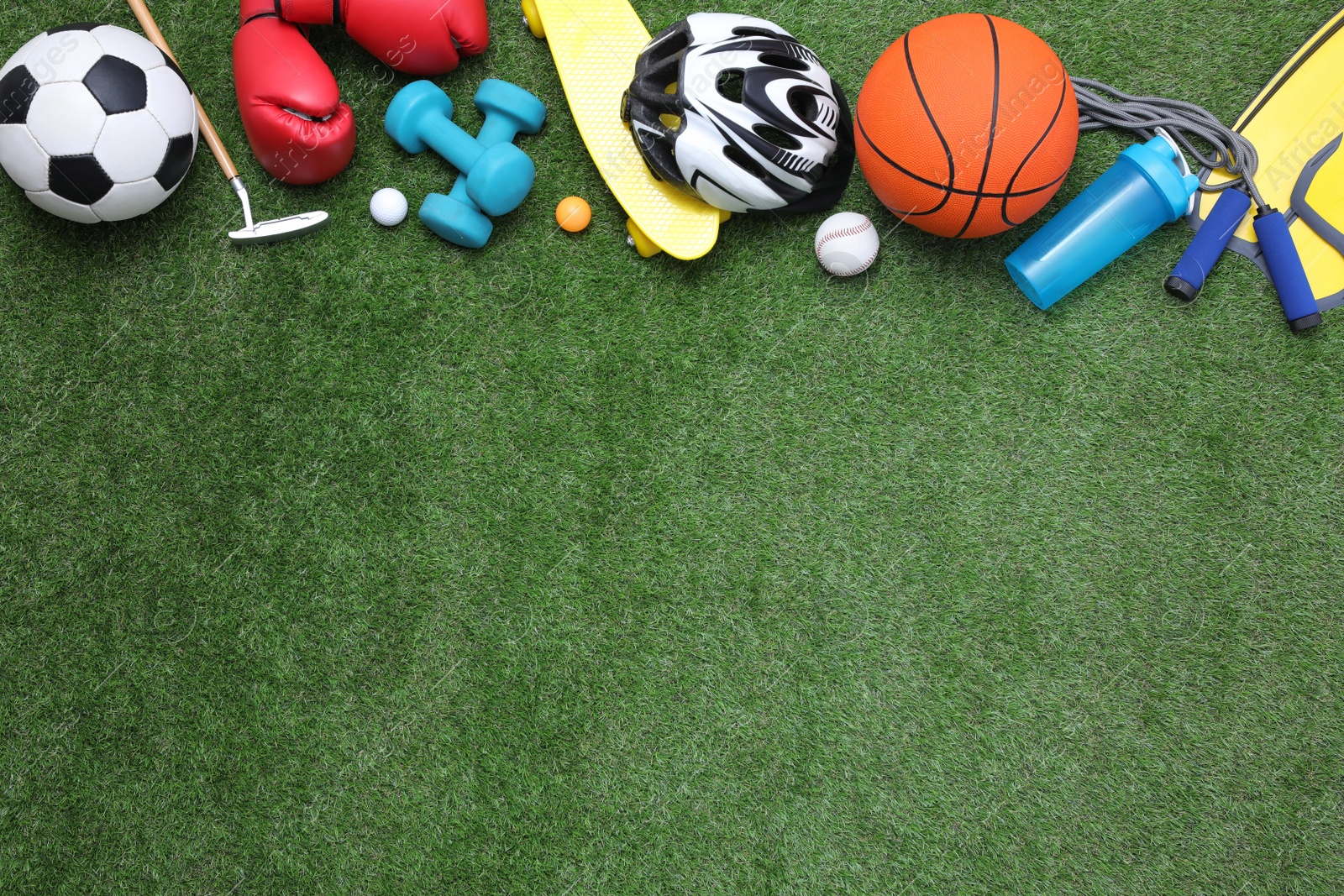 Photo of Different sport equipment on green grass, flat lay. Space for text