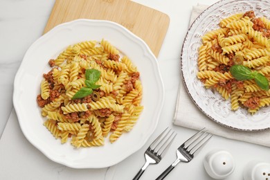 Photo of Delicious pasta with minced meat and basil served on white table, flat lay