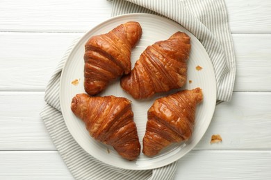 Plate with tasty croissants on white wooden table, top view