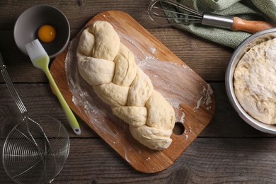 Photo of Homemade braided bread and ingredients on wooden table, flat lay. Cooking traditional Shabbat challah