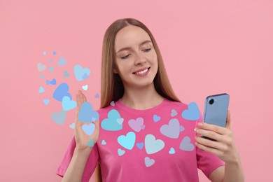 Long distance love. Woman video chatting with sweetheart via smartphone on pink background. Hearts flying out of device