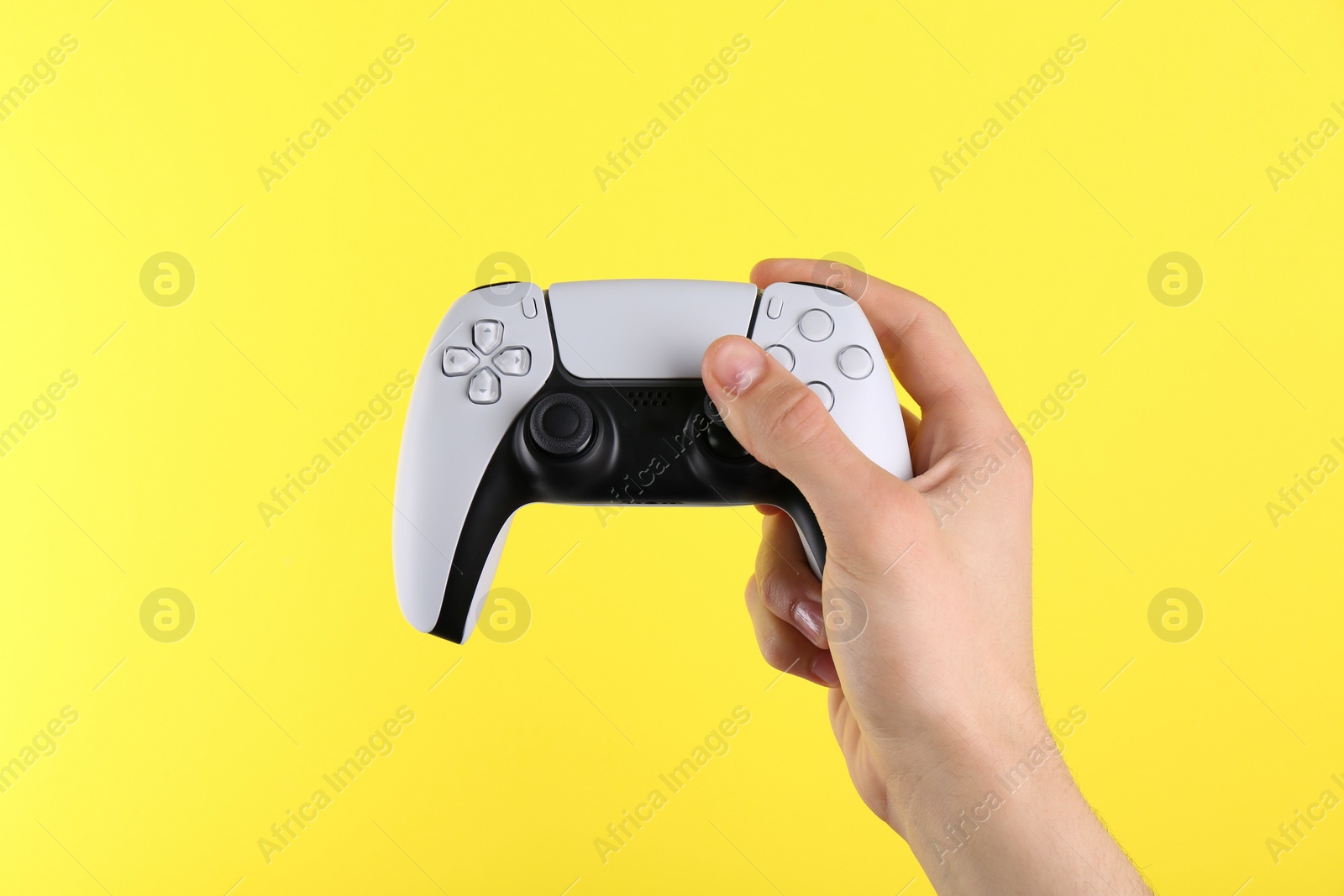 Photo of Man holding wireless game controller on yellow background, closeup