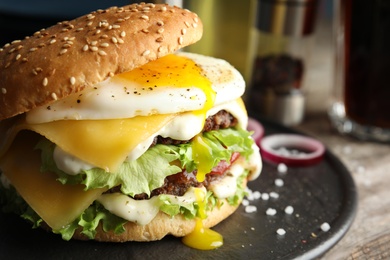 Photo of Tasty burger with fried egg on tray against blurred background, space for text