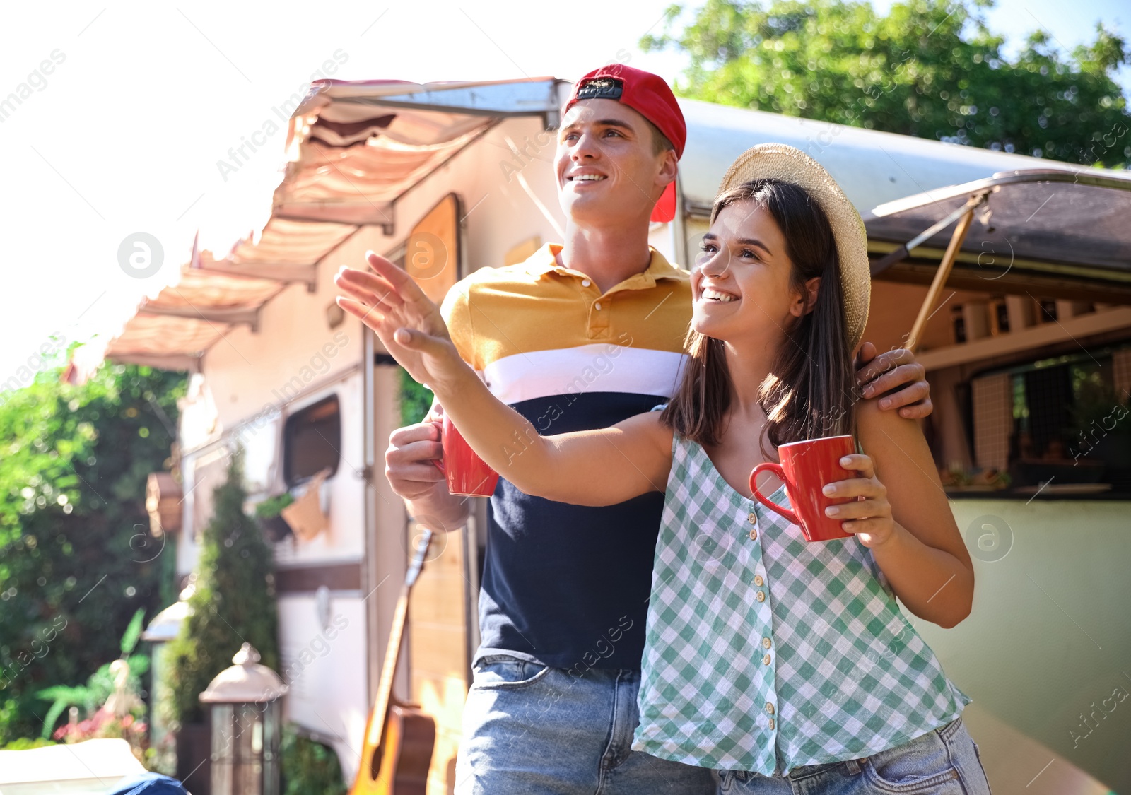 Photo of Happy couple with cups near motorhome. Camping season