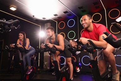 Group of people training on exercise bikes in fitness club