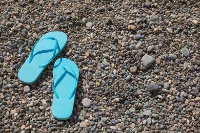 Stylish turquoise flip lops on pebble beach, above view. Space for text