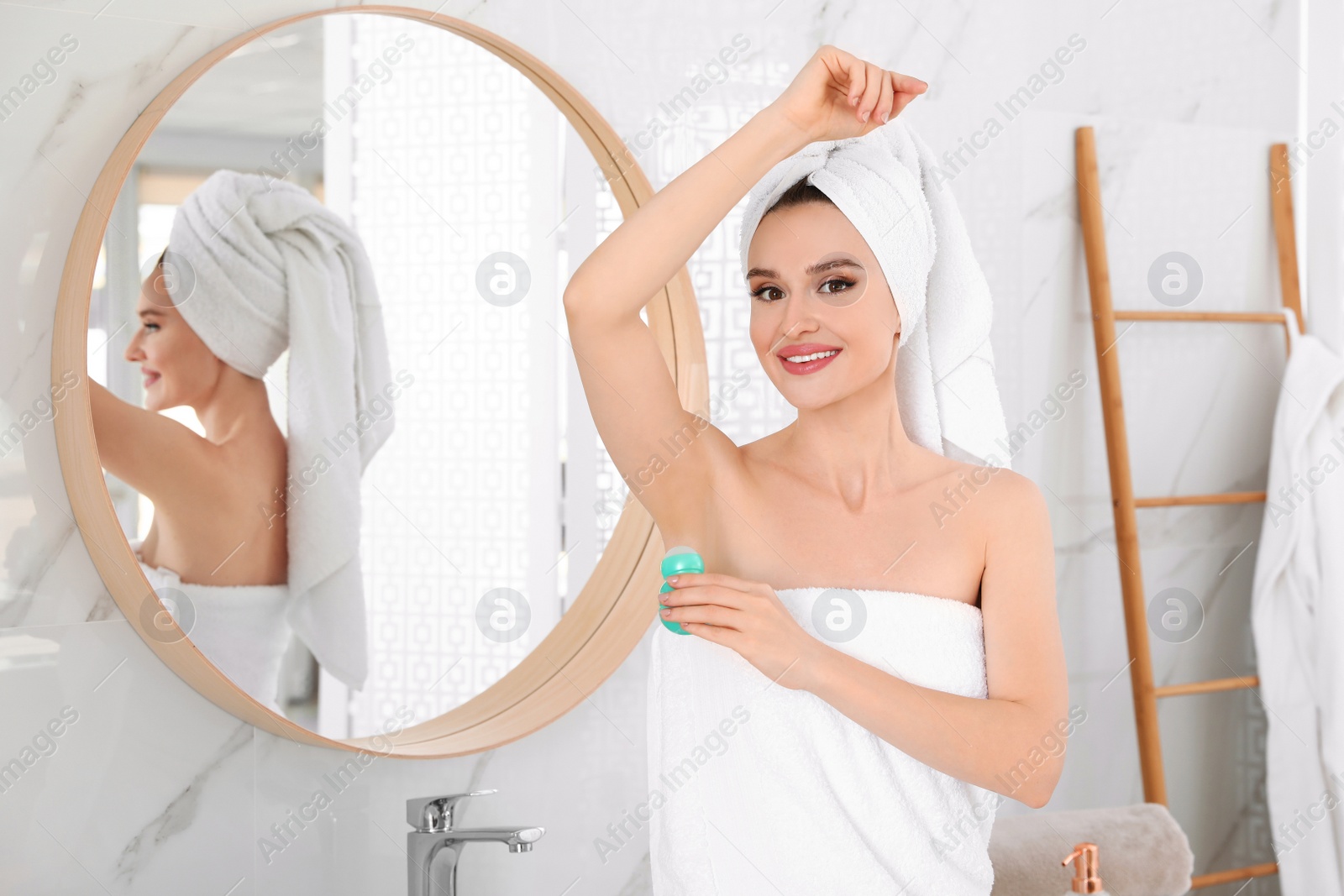 Photo of Beautiful young woman applying deodorant after shower in bathroom