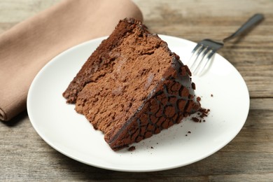 Photo of Piece of delicious chocolate truffle cake and fork on wooden table, closeup