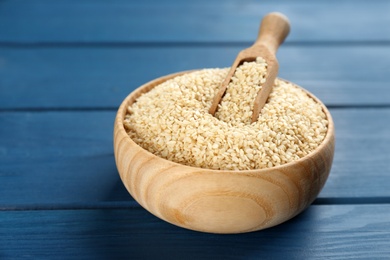 Photo of Bowl with sesame seeds and scoop on blue wooden table
