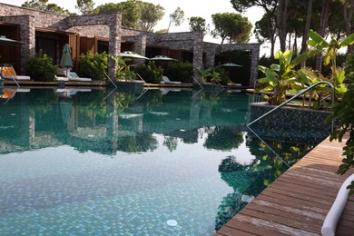 Photo of Swimming pool, exotic plants and sunbeds at luxury resort