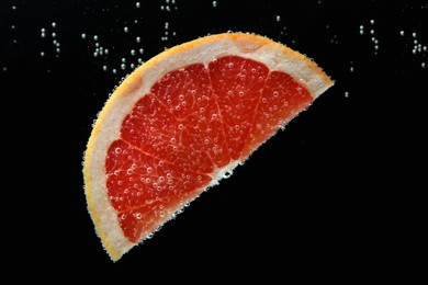 Slice of grapefruit in sparkling water on black background. Citrus soda
