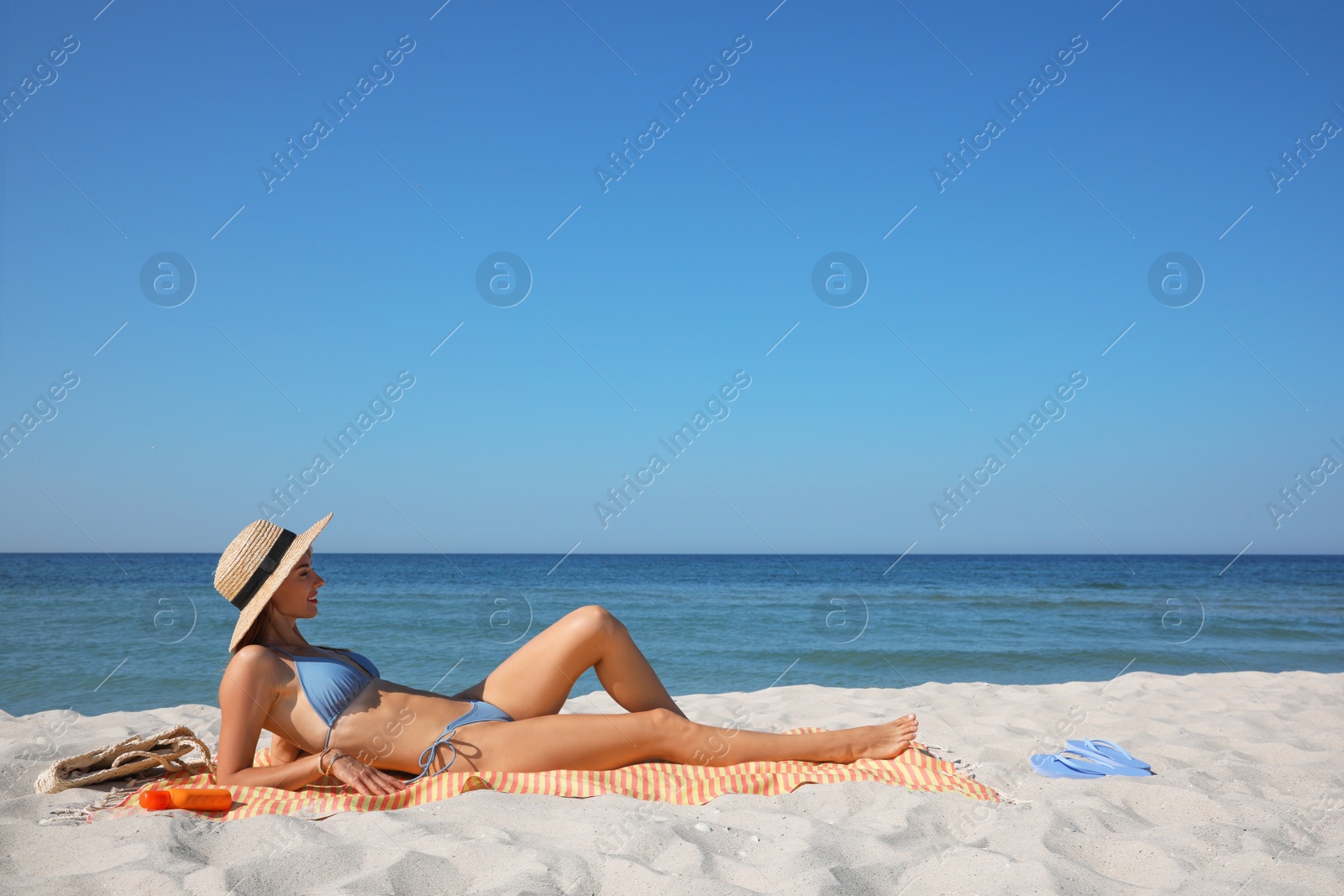 Photo of Woman with towel and other beach stuff on sand near sea