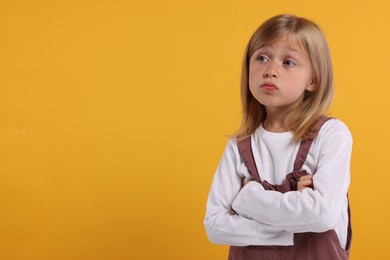 Photo of Resentful girl with crossed arms on orange background. Space for text