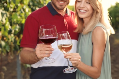 Young couple holding glasses of wine at vineyard