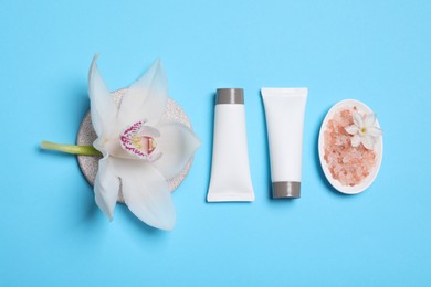 Flat lay composition with spa products and beautiful flower on light blue background