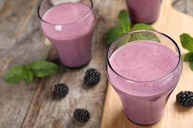 Photo of Glasses with tasty blackberry yogurt smoothies on table