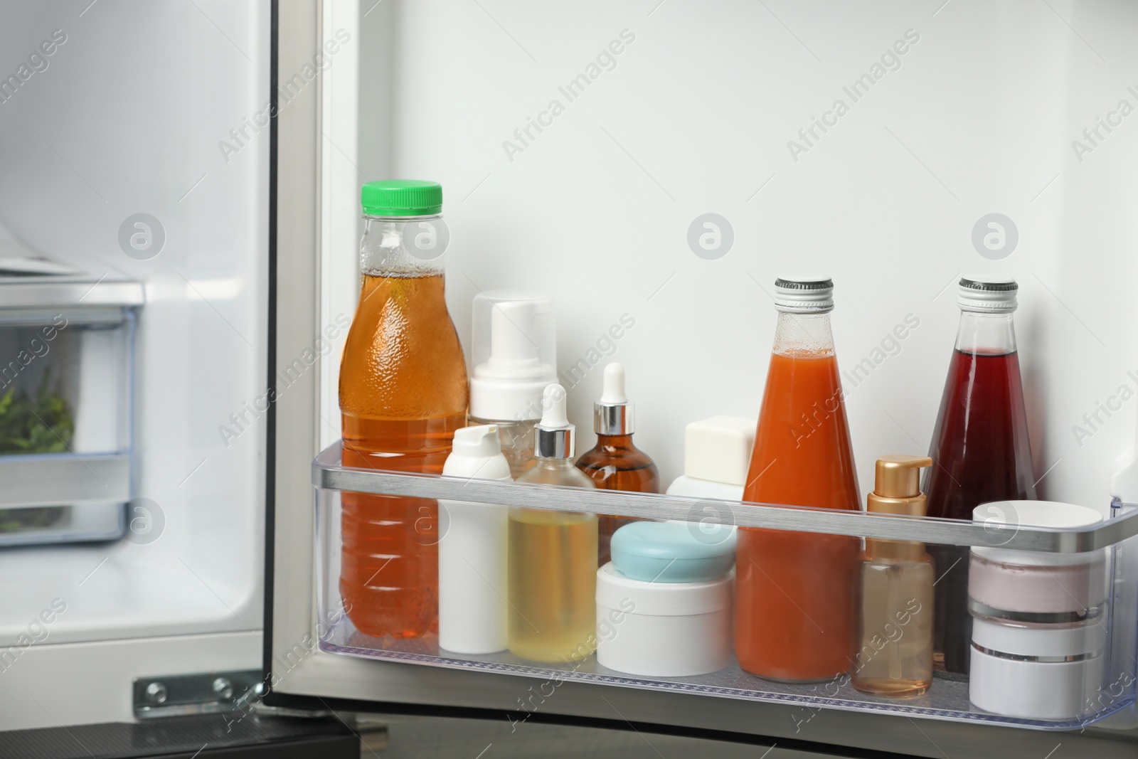 Photo of Different cosmetic products on shelf in refrigerator