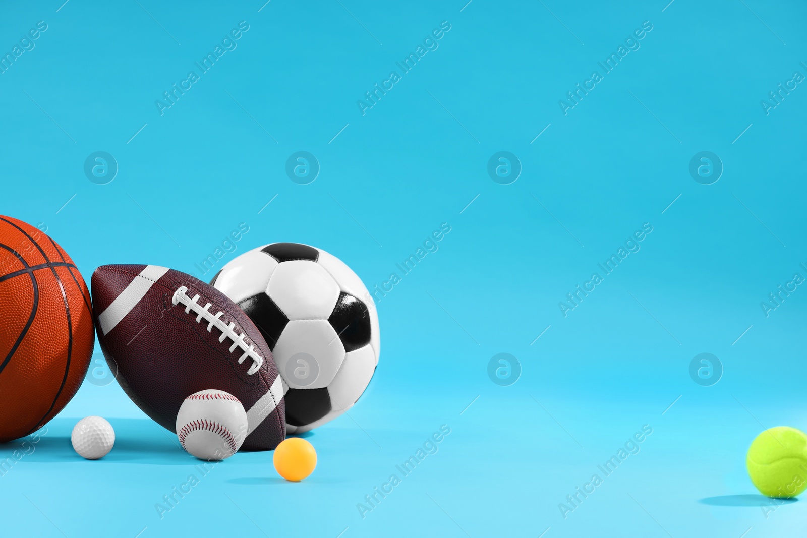 Photo of Many different sports balls on light blue background, space for text