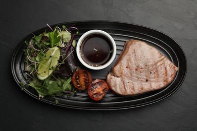 Photo of Delicious tuna steak served on black table, top view