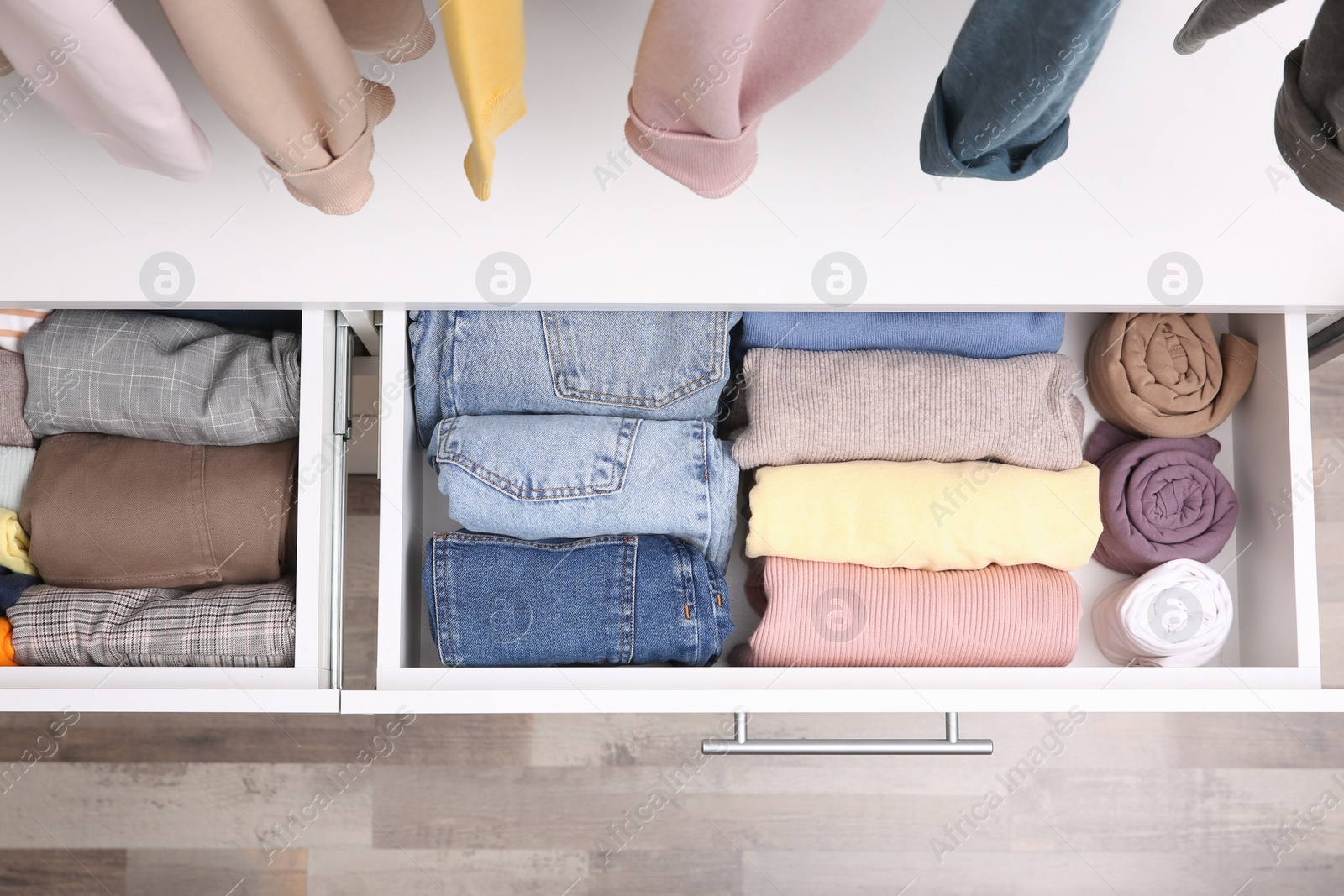 Photo of Open drawers with folded clothes indoors, top view. Vertical storage