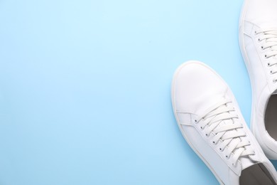 Photo of Pair of stylish white sneakers on light blue background, top view. Space for text