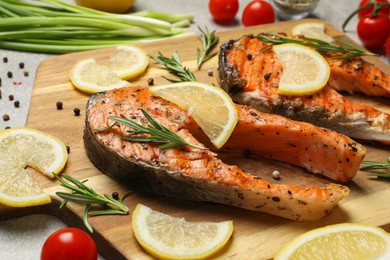 Photo of Tasty grilled salmon steaks and different ingredients on light grey table