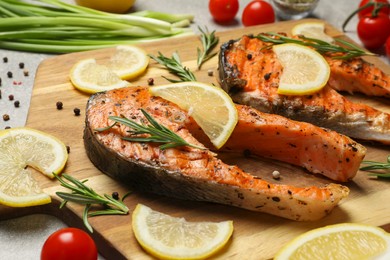 Tasty grilled salmon steaks and different ingredients on light grey table